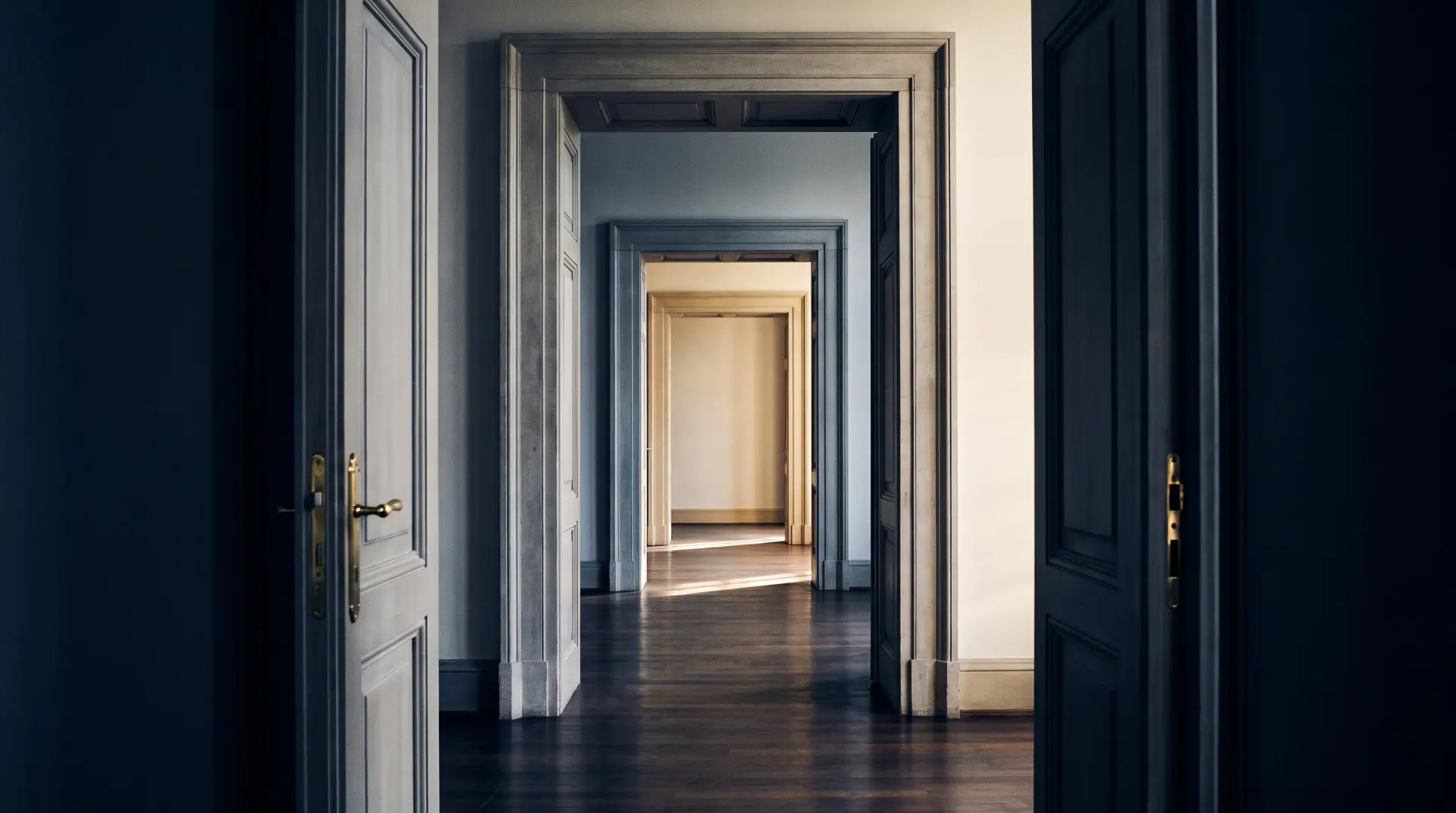Corredor de portas sucessivas em tons navy e marfim, com luz dourada ao fundo